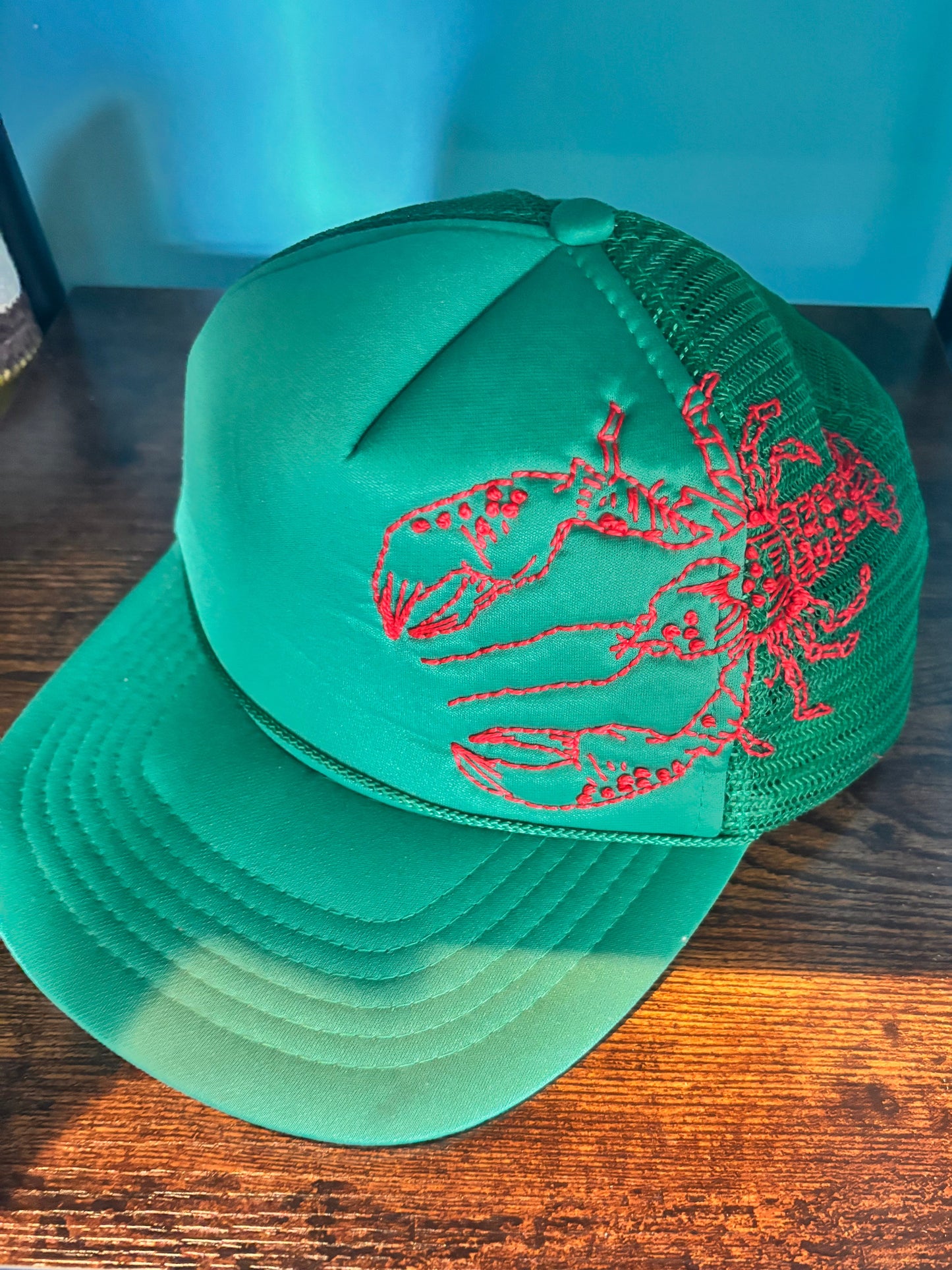 Green cap with red lobster hand-embroidered on the side. 