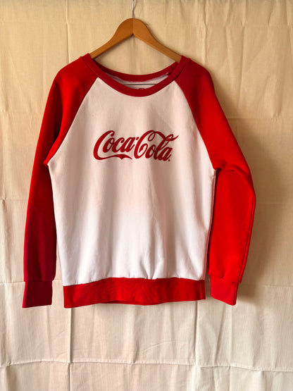 Red and white sweatshirt with Coca-Cola logo on a beige background