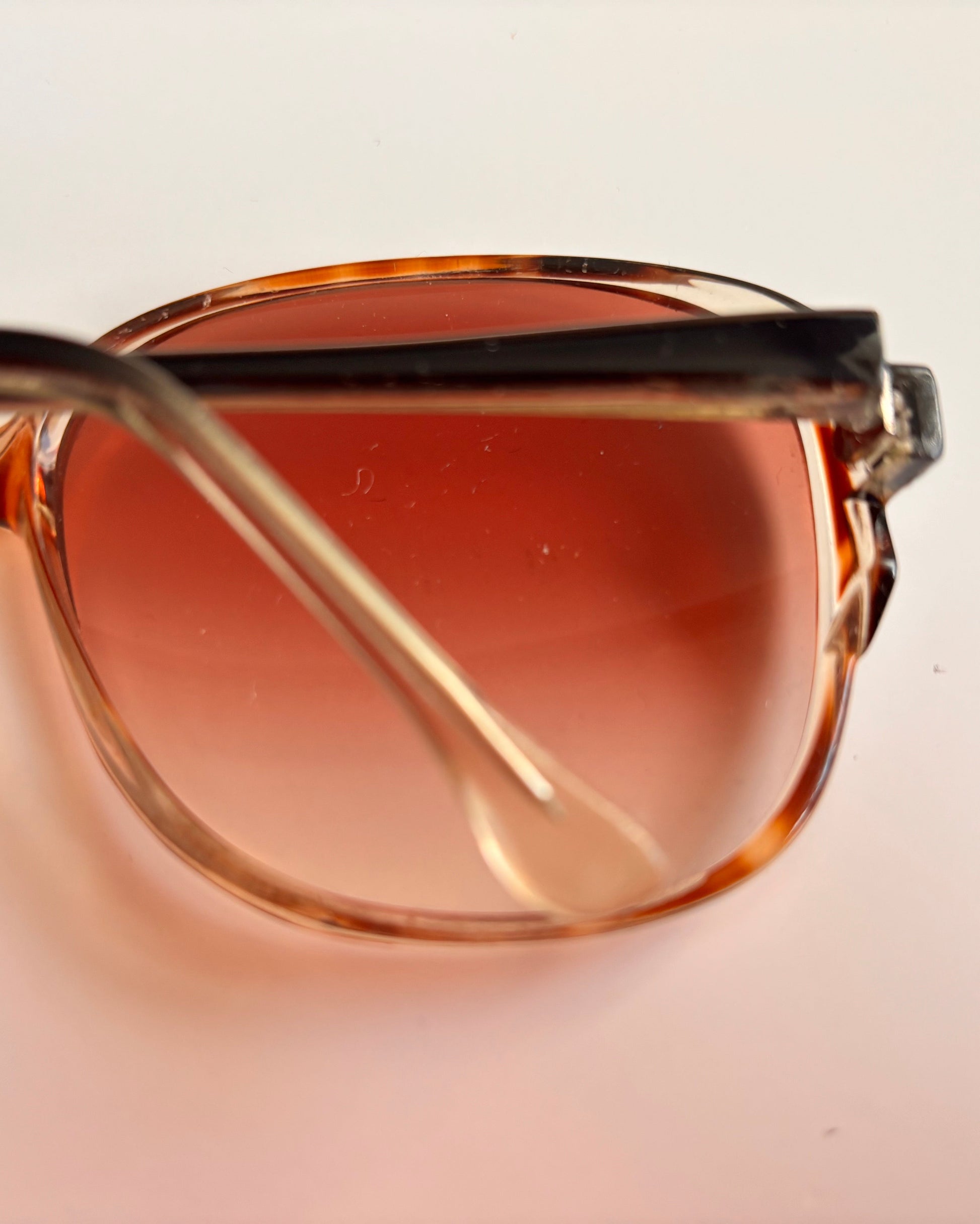 Sunglasses with brown gradient lenses on a light beige background