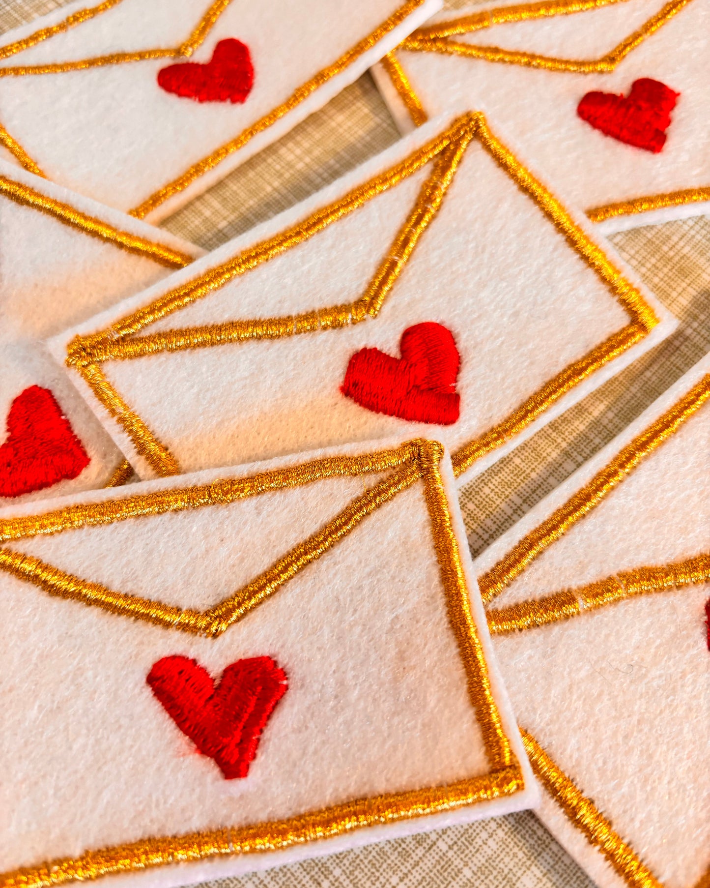 Close-up of embroidered love letter iron on embroidery patches with red hearts and gold borders.