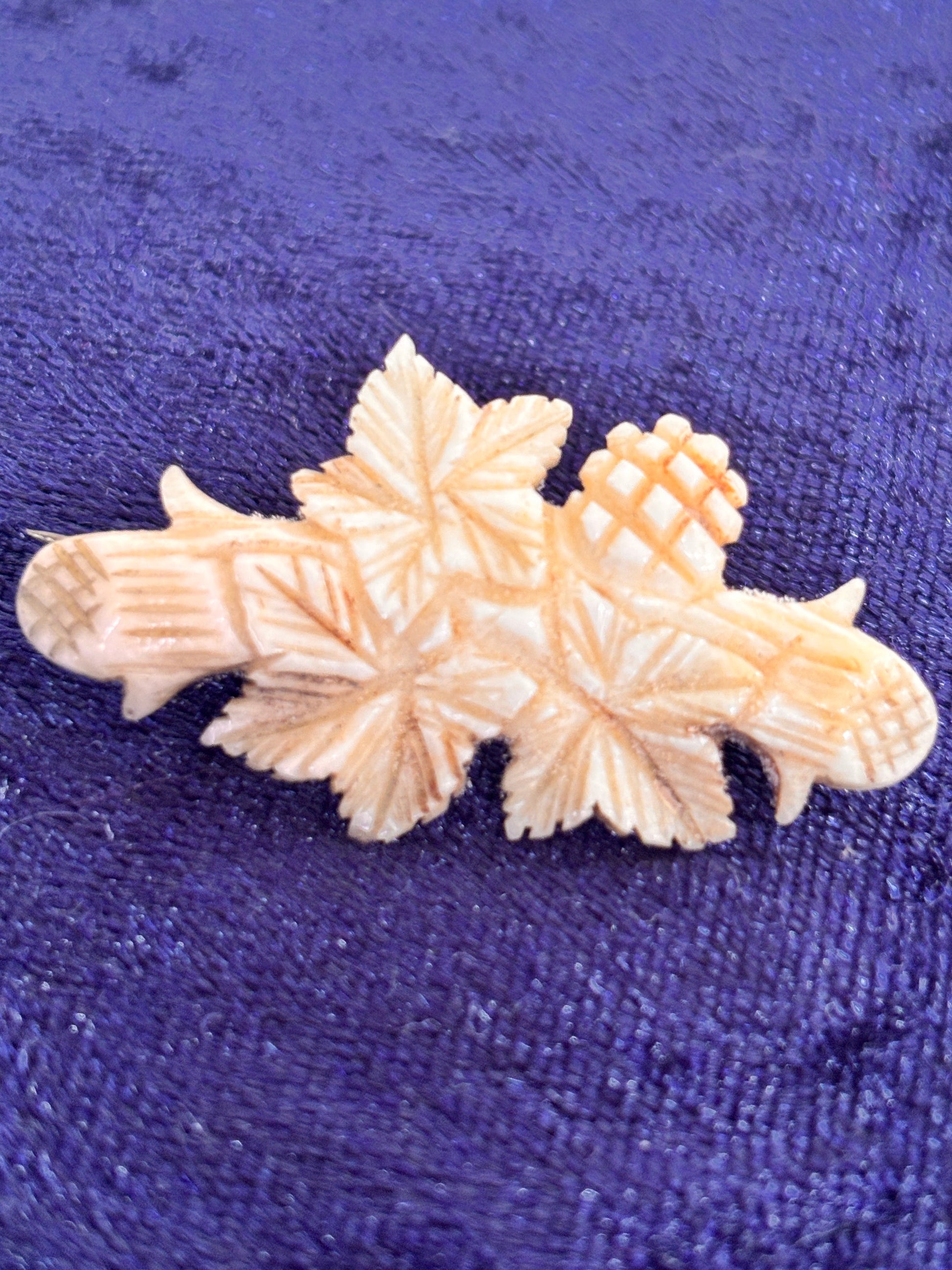 Vintage carved bone brooch in Black Forest style on a textured blue fabric background