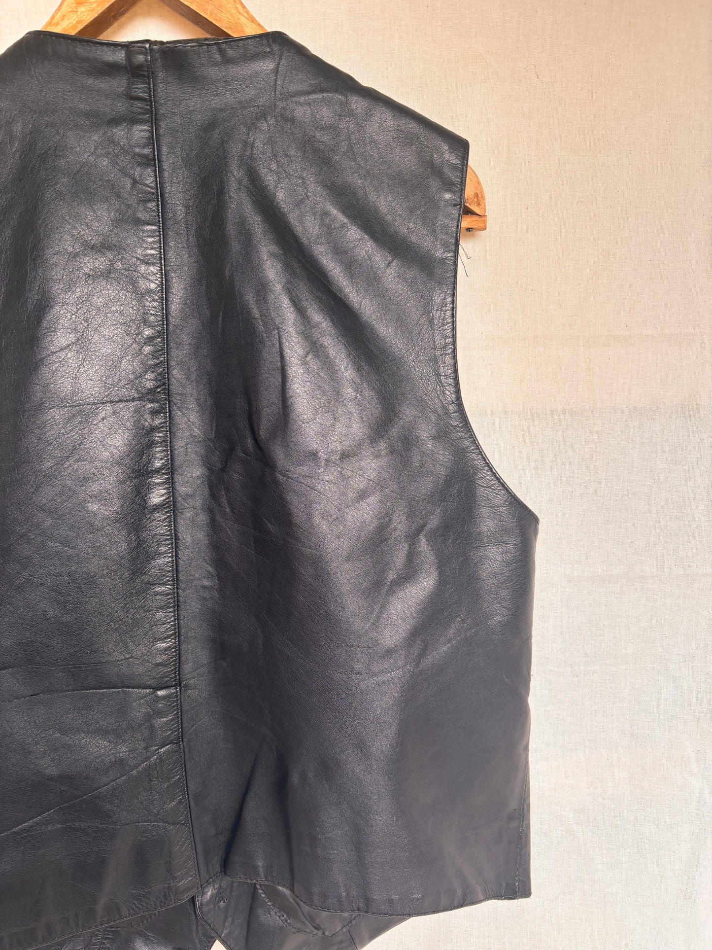 back view of Vintage 1980s Black Leather Waistcoat Vest on hanger